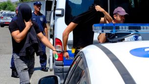 اثنين من المشتبه بهم باغتصاب جماعي لسائحة بريطانية يغطون وجوههم بمساعدة ملابسهم اثناء وصولهم الى محكمة فاماغوستا في بلدة بارالامني في قبرص، 18 يوليو 2019 (AP Photo/Petros Karadjias)