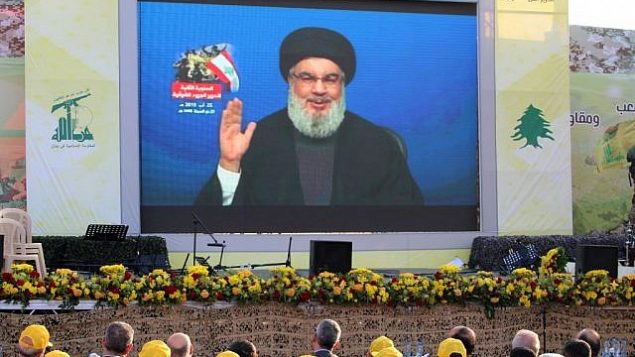 مناصرو منظمة حزب الله الشيعية اللبنانية يحتشدون لمتابعة نقل كلمة الأمين العام للمنظمة، حسن نصر الله، على شاشة كبيرة في بلدة العين في منطقة سهل البقاء اللبنانية، 25 أغسطس، 2019. (AFP)