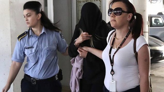 شرطيتان ترافقان شابة بريطانية (19 عاما)، وسط، خارج محكمة فاماغوستا في مدينة بالارميني القبرصية، 29 يوليو، 2019.  (AP/Petros Karadjias)