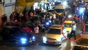 ضابط شرطة (في الدائرة الحمراء) يطلق النار في الهواء لتفريق مجموعة من الشبان اعتدت على سائق مركبة يهودي في شارع ’صلاح الدين’ بالقدس، 11 أغسطس، 2019. (فيديو لشرطة إسرائيل)