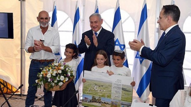 (من اليسار إلى اليمين) رئيس المجلس الإقليمي غور الأردن، دافيد إلحياني، ورئيس الوزراء بنيامين نتنياهو، وسكرتير الحكومة تساحي برافرمان، يصفقون بعد أن صادقت الحكومة على شرعنة بؤرة ميفؤوت يريحو الاستيطانية في الجلسة الأسبوعية للحكومة التي عُقدت في غور الأردن، 15 سبتمبر، 2019.  (Haim Tzach/GPO)