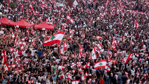 متظاهرون لبنانيون يلوحون بالأعلام الوطنية أثناء مشاركتهم في مظاهرة في وسط العاصمة بيروت, 20 أكتوبر 2019. (Patrick Baz/AFP)