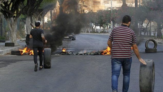 متظاهرون لبنانيون مناهضون للحكومة يسدون طريقاً بإطارات محترقة في مدينة صيدا الساحلية الجنوبية، 21 أكتوبر 2019 (Mahmoud ZAYYAT / AFP)