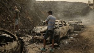 أشخاص يتفقدون حطام مركبات ومحلات تجارية أتت عليها النيران جراء حرائق اندلعت فجرا في بلدة دامور التي تبعد 15 كيلومترا جنوب بيروت، لبنان، 15 أكتوبر، 2019.  (AP Photo/Hassan Ammar)