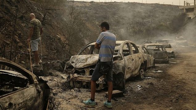 أشخاص يتفقدون حطام مركبات ومحلات تجارية أتت عليها النيران جراء حرائق اندلعت فجرا في بلدة دامور التي تبعد 15 كيلومترا جنوب بيروت، لبنان، 15 أكتوبر، 2019.  (AP Photo/Hassan Ammar)