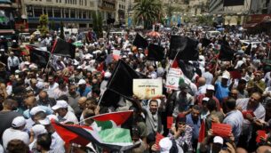 متظاهرون فلسطينيون يحملون لافتات وأعلام وطنية خلال مظاهرة على مؤتمر الشرق الأوسط الاقتصادي الذي ترعاه الولايات المتحدة والذي افتتح في البحرين، في مدينة نابلس بالضفة الغربية، 25 يونيو 2019. (Jaafar Ashtiyeh/AFP)