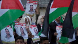 متظاهرون يحملون الأعلام الفلسطينيون ولافتات تحمل صور الأسير الفلسطيني في السجون الإسرائيلية، سامي أبو دياك، الذي توفي بعد صراع مع مرض السرطان، خلال تظاهرة في مدينة رام الله بالضفة الغربية، 26 نوفمبر، 2019.  (AP Photo/Nasser Nasser)