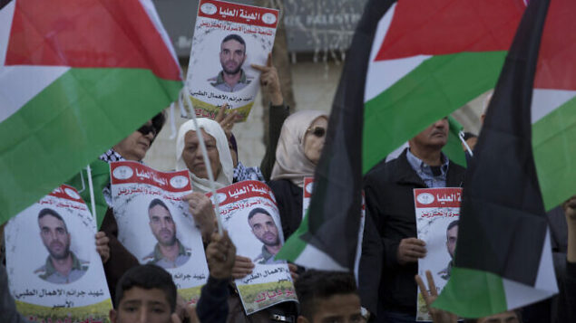 متظاهرون يحملون الأعلام الفلسطينيون ولافتات تحمل صور الأسير الفلسطيني في السجون الإسرائيلية، سامي أبو دياك، الذي توفي بعد صراع مع مرض السرطان، خلال تظاهرة في مدينة رام الله بالضفة الغربية، 26 نوفمبر، 2019.  (AP Photo/Nasser Nasser)