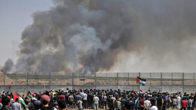 فلسطينيون يتظاهرون امام السياج الحدودي مع اسرائيل شرقي مدينة غزة، بينما يتصاعد الدخان من حرائق ناتجة عن بالونات حارقة، 15 مايو 2019 (MAHMUD HAMS / AFP)