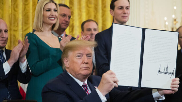 President Donald Trump shows the executive order he signed combatting anti-Semitism in the U. S. during a Hanukkah reception in the East Room of the White House Wednesday, Dec. 11, 2019, in Washington. (AP Photo/Manuel Balce Ceneta)