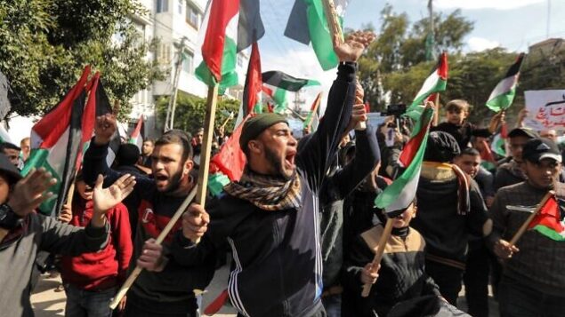 متظاهرون فلسطينيون يهتفون شعارات ويرفعون الأعلام الفلسطينية في تظاهرة ضد خطة السلام المتوقعة للرئيس الأمريكي دونالد ترامب في مدينة غزة في 28 يناير، 2020.   (MAHMUD HAMS / AFP)