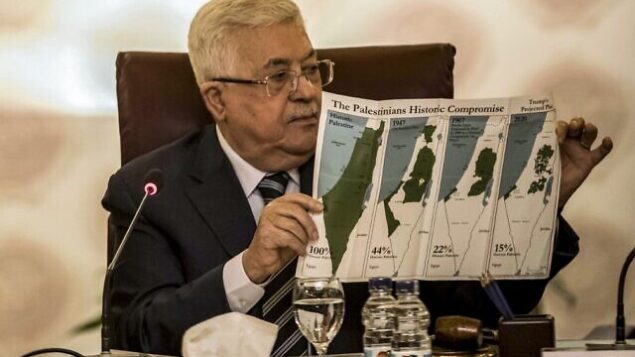 رئيس السلطة الفلسطينية محمود عباس يحمل ورقة تظهر خرائط (من اليسار إلى اليمين) "فلسطين التاريخية"، قرار الأمم المتحدة لتقسيم فلسطين 1947، الحدود بين الأراضي الفلسطينية وإسرائيل 1948-1967، وخريطة حالية للأراضي الفلسطينية الغير خاضعة للسيطرة الإسرائيلية والمستوطنات، خلال جلسة طارئة لجامعة الدول العربية لمناقشة خطة اقتراح الرئيس الأمريكي دونالد ترامب للسلام، في مقر الجامعة العربية في العاصمة المصرية القاهرة، 1 فبراير، 2020. (Khaled Desouki/AFP)