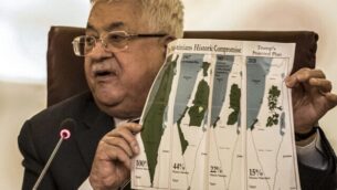 رئيس السلطة الفلسطينية محمود عباس يحمل ورقة تظهر خرائط (من اليسار إلى اليمين) "فلسطين التاريخية"، قرار الأمم المتحدة لتقسيم فلسطين 1947، الحدود بين الأراضي الفلسطينية وإسرائيل 1948-1967، وخريطة حالية للأراضي الفلسطينية الغير خاضعة للسيطرة الإسرائيلية والمستوطنات، خلال جلسة طارئة لجامعة الدول العربية لمناقشة خطة اقتراح الرئيس الأمريكي دونالد ترامب للسلام، في مقر الجامعة العربية في العاصمة المصرية القاهرة، 1 فبراير، 2020. (Khaled Desouki/AFP)