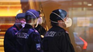شرطيون يضعون أقنعة واقية خلال إغلاقهم لفندق بالقرب من مدينة إنسبروك النمساوية، في 25 فبراير، 2020 بعد أن تم تأكيد إصابة امرأة عملت هناك بفيروس كورونا.  ( Johann GRODER / APA / AFP)