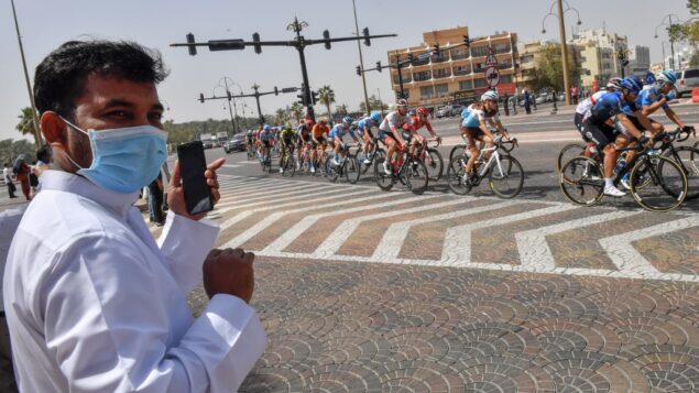 رجل يرتدي قناع جراحي ينظر بينما تنطلق المجموعة خلال المرحلة الخامسة من جولة الإمارات للدراجات من المروم إلى جبل حفيت، في دبي، 27 فبراير 2020. (Giuseppe CACACE / AFP)
