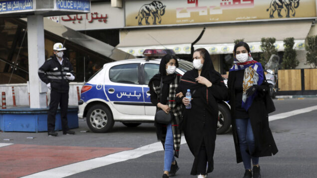 صورة توضيحية: أحد رجال الشرطة والمشاة يرتدون أقنعة للحماية من فيروس كورونا، في وسط طهران، إيران، 23 فبراير 2020. (Ebrahim Noroozi / AP)