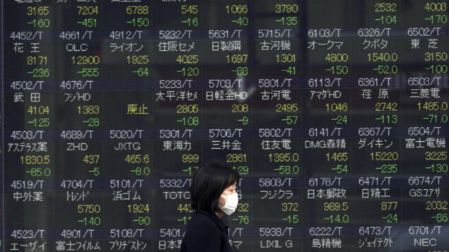 صورة توصيحية: امرأة تسير امام لوحة أسهم إلكترونية تعرض مؤشر Nikkei 225 الياباني في إحدى شركات الأوراق المالية في طوكيو، 25 فبراير 2020 (AP / Eugene Hoshiko)