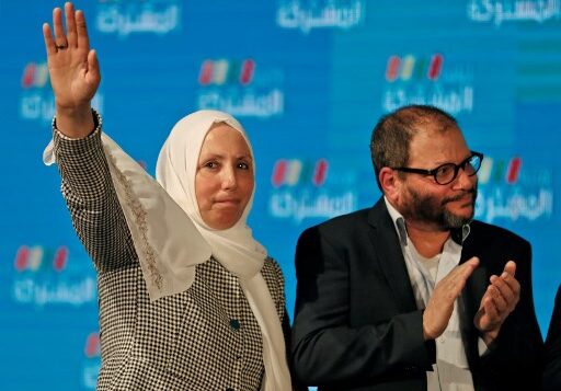 إيمان خطيب ياسين، السياسية الإسرائيلية العربية التي تمثل الفرع الجنوبي للحركة الإسلامية في تحالف القائمة المشتركة، ترفع يدها بينما تقف بجانب عوفر كاسيف، العضو اليهودي في القائمة ومرشح حزب الجبهة في التحالف، بينما يقفان امام أنصار القائمة في مقرهم الانتخابي في مدينة شفا عمرو بشمال إسرائيل، 2 مارس 2020 (Ahmad GHARABLI / AFP)