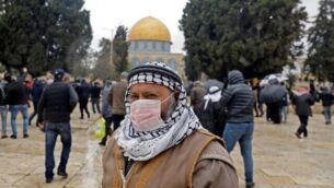 رجل فلسطيني يرتدي قناعا واقيا كإجراء حماية ضد فيروس كورنا COVID-19، يقف أمام قبة الصخرة في الحرم القدسي بالبلدة القديمة، قبل صلاة الجمعة،   6 مارس، 2020. (Ahmad Gharabli/AFP)