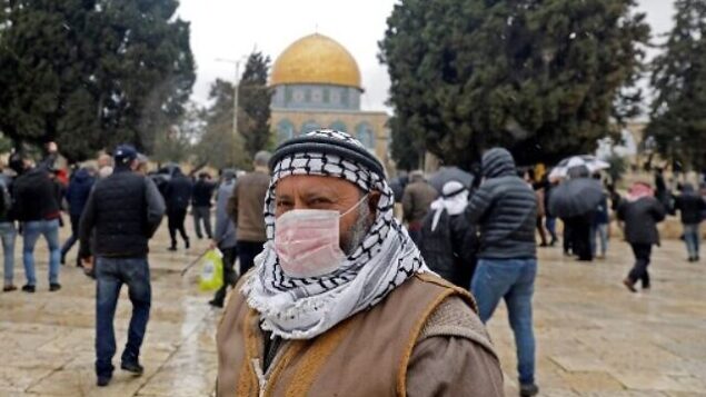 رجل فلسطيني يرتدي قناعا واقيا كإجراء حماية ضد فيروس كورنا COVID-19، يقف أمام قبة الصخرة في الحرم القدسي بالبلدة القديمة، قبل صلاة الجمعة،   6 مارس، 2020. (Ahmad Gharabli/AFP)