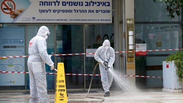رجال إطفاء إسرائيليون يقومون بإجراءات تعقيم عند مدخل المركزالطبي "سوراسكي" في مدينة تل أبيب، 20 مارس، 2020. (Photo by JACK GUEZ / AFP)