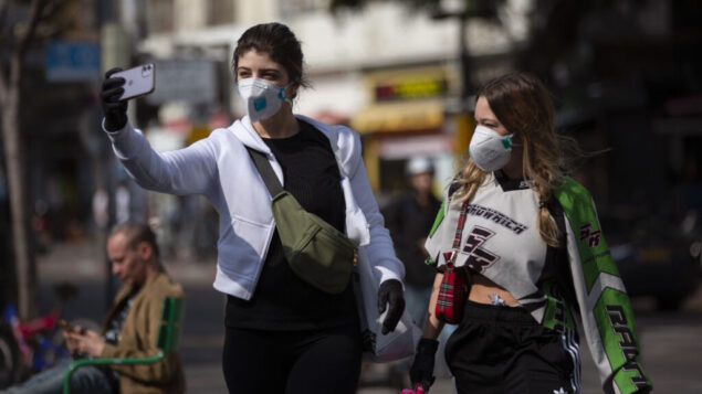 امرأتان تلتقطان صورة سلفي مع أقنعة الوجه في تل أبيب، 15 مارس 2020 (AP / Oded Balilty)
