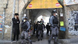 عناصر شرطة إسرائيلية في حي ’مئة شعاريم’ الحريدي بالقدس يقومون بإغلاق المحلات التجارية وتفريق التجمعات العامة عقب قرارات الحكومة التي صدرت في محاولة لاحتواء انتشار فيروس كورونا، 24 مارس، 2020. (Yonatan Sindel/Flash90)