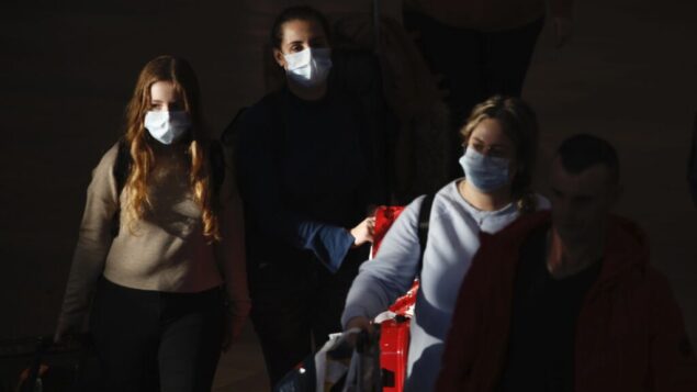 صورة توضيحية: مسافرون يرتدون أقنعة واقية يصلون إلى مطار بن غوريون، 27 فبراير 2020. (AP Photo / Ariel Schalit) صورة توضيحية: مسافرون يرتدون أقنعة واقية يصلون إلى مطار بن غوريون، 27 فبراير 2020. (AP Photo / Ariel Schalit)