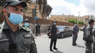 ضباط يقفون عند وصول قافلة تنقل رئيس الوزراء بنيامين نتنياهو إلى محكمة القدس المركزية، 24 مايو 2020 (Menahem KAHANA / AFP)