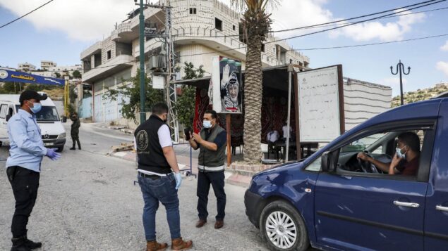 قوات الأمن الفلسطينية تقف عند نقطة تفتيش في قرية تفوح، غرب الخليل في الضفة الغربية، 19 يونيو 2020 (HAZEM BADER / AFP)