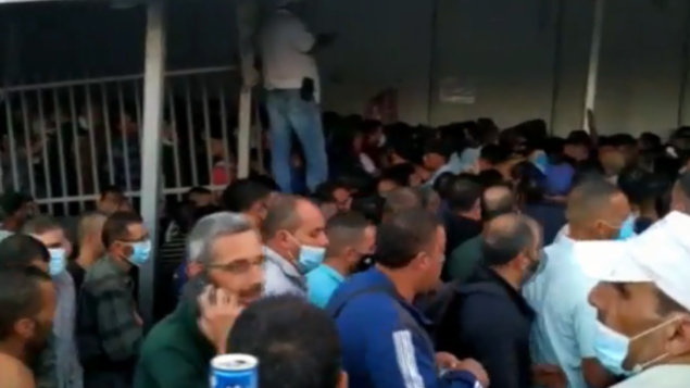 عمال فلسطينيون في طريقهم إلى العمل في إسرائيل، عند حاجز 300 في بيت لحم بالضفة الغربية، يونيو 2020.(Screenshot: Channel 12)