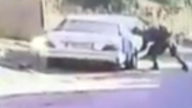 جندي اسرائيلي يقوم على ما يبدو بتمزيق إطارات سيارة ليموزين فلسطينية في قرية كفر قدوم خلال مظاهرة، 30 مايو 2020 (screen capture: B’Tselem)