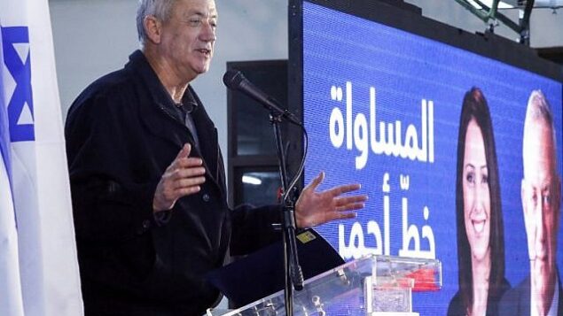 الجنرال الإسرائيلي المتقاعد بيني غانتس، أحد قادة تحالف ’أزرق أبيض’ السياسي، يلقي كلمة وإلى جانبه شاشة عملاقة تعرض صورته إلى جانب عبارة ’المساواة خط أحمر’ خلال لقاء مع قادة دروز في بلدة دالية الكرمل في شمال إسرائيل، 7 مارس، 2019.(JACK GUEZ / AFP)