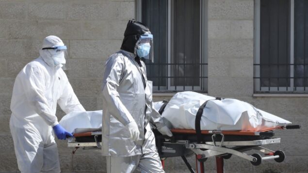 فريق طبي فلسطيني ينقل جثمان شخص توفى نتيجة مرض كوفيد-19 من المستشفى العسكري في مدينة نابلس بالضفة الغربية، 9 يوليو 2020. (JAAFAR ASHTIYEH / AFP)