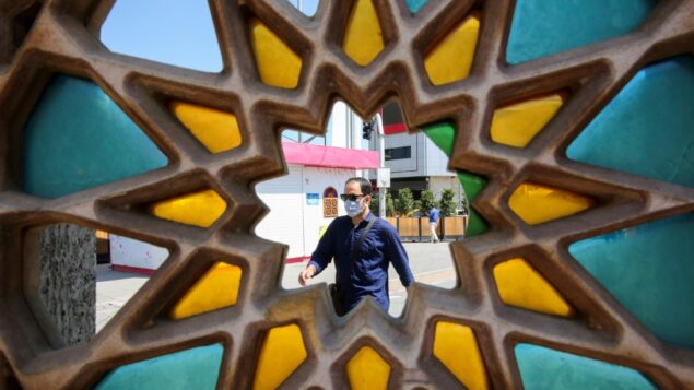 رجل إيراني يرتدي قناع وجه واقٍ، يسير في شارع في العاصمة طهران، 22 يوليو 2020. (ATTA KENARE / AFP)
