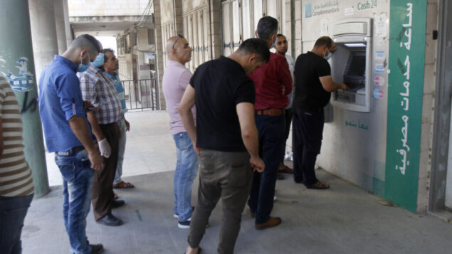 صورة توضيحية: فلسطينيون ينتظرون في طابور امام جهاز صراف آلي في مدينة نابلس بالضفة الغربية، 2 يوليو 2020. (Nasser Ishtayeh/Flash90)