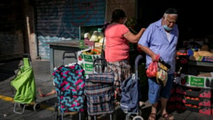 أشخاص يرتدون أقنعة الوجه بسبب تفشي فيروس كورونا ستيوقون في سوق محانيه يهودا في القدس، 21 يوليو 2020. (Olivier Fitoussi / Flash90)