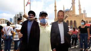 رجل يقف لالتقاط صورة مع مجسمات لحسن نصر الله (يسار)، زعيم حزب الله، ووزير الخارجية اللبناني السابق جبران باسيل، شنقها متظاهرون في وسط بيروت، 8 أغسطس 2020 (AFP)