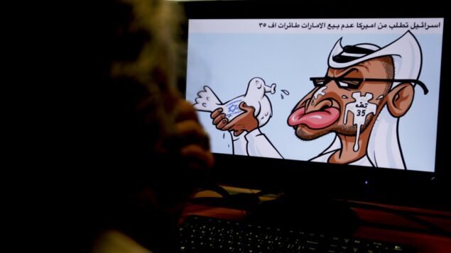 امرأة تنظر إلى رسم كاريكاتوري لرسام الكاريكاتير الأردني عماد الحجاج يصور زعيم دولة الإمارات العربية المتحدة الشيخ محمد بن زايد آل نهيان وهو يحمل حمامة عليها علم إسرائيل، وتبصق في وجهه، وتشير كتابة عربية إلى معارضة إسرائيل لبيع طائرات أمريكية من طراز إف-35 للإمارات، 27 أغسطس 2020 (AFP)