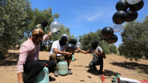 فلسطينيون يستعدون لإطلاق بالونات باتجاه إسرائيل، بالقرب من الحدود بين إسرائيل وغزة، في الجزء الشرقي من قطاع غزة، 10 أغسطس، 2020. (Abed Rahim Khatib / Flash90)