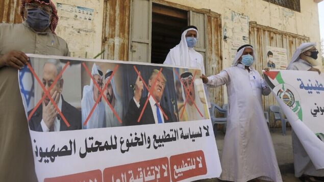 فلسطينيون يحملون ملصقًا به صور مشطوبة لرئيس الوزراء بنيامين نتنياهو، ولي عهد أبوظبي محمد بن زايد آل نهيان، حاكم دبي محمد بن راشد آل مكتوم، الرئيس الأمريكي دونالد ترامب والملك البحريني حمد بن عيسى آل خليفة خلال مسيرة نظمتها حركة حماس في مدينة دير البلح وسط غزة، لإدانة اتفاق التطبيع الإسرائيلي البحريني، 12 سبتمبر 2020 (Mahmud Hams/AFP)