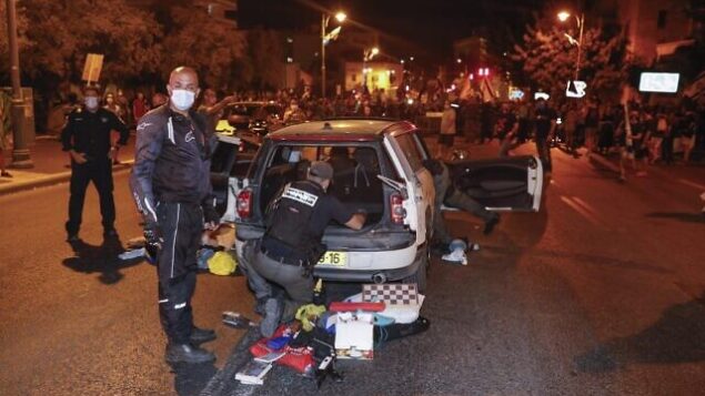 عناصر من الشرطة يفتشون سيارة رجل اندفع باتجاه الشرطة والمتظاهرين خلال مظاهرة ضد رئيس الوزراء بنيامين نتنياهو، خارج مقر إقامته الرسمي في القدس، 20 سبتمبر 2020 (Ahmad GHARABLI / AFP) عناصر من الشرطة يفتشون سيارة رجل اندفع باتجاه الشرطة والمتظاهرين خلال مظاهرة ضد رئيس الوزراء بنيامين نتنياهو، خارج مقر إقامته الرسمي في القدس، 20 سبتمبر 2020 (Ahmad GHARABLI / AFP)