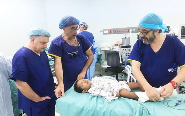 Australian medical personnel (from left) Michael Gordon, Rob Berkowitz and Mark Fajgman treat a young patient in Fiji.