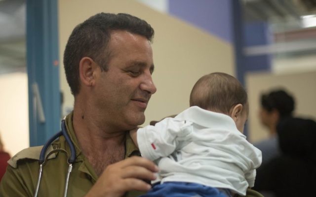 An Israeli medic helping a Syrian child.