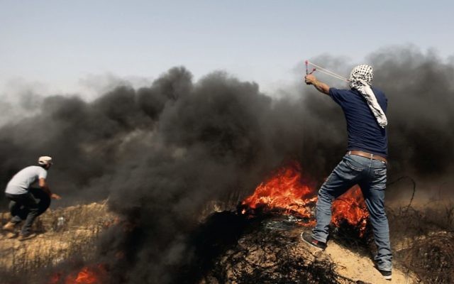 Palestinians hurl stones and burning tires near the Gaza border earlier this month. Photo: AP Photo/Adel Hana Palestinians hurl stones and burning tires near the Gaza border earlier this month. Photo: AP Photo/Adel Hana