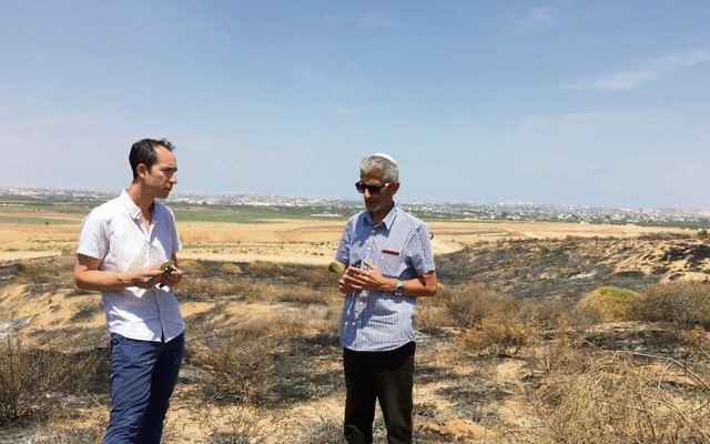 The AJN's Nathan Jeffay (left) with Eyal Hagbi on a patch of land scorched by a kite fire.