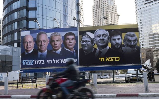 An Israeli motorcyclist passes billboards put up by the Blue and White
alliance featuring their candidate for prime minister, Benny Gantz, alongside
his fellow party leaders next to a panel showing Benjamin Netanyahu and
extreme right-wing politicians. On the right side the Hebrew translates as
“Kahane lives” and on the left reads, “People of Israel live Blue and White”. Photo: EPA/Jim Hollander An Israeli motorcyclist passes billboards put up by the Blue and White
alliance featuring their candidate for prime minister, Benny Gantz, alongside
his fellow party leaders next to a panel showing Benjamin Netanyahu and
extreme right-wing politicians. On the right side the Hebrew translates as
“Kahane lives” and on the left reads, “People of Israel live Blue and White”. Photo: EPA/Jim Hollander
