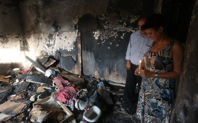 Israeli peace activists hold a candle in the Dawabsheh family's burnt-out home.
Photo: AFP Photo/Jaafar Ashtiyeh Israeli peace activists hold a candle in the Dawabsheh family's burnt-out home.
Photo: AFP Photo/Jaafar Ashtiyeh