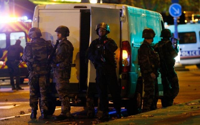 French army and police take cover outside the  Bataclan theatre in Paris. Photo:  EPA/YOAN VALAT
