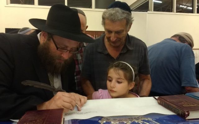Rabbi Gutnick writing in the Torah with Tony and Maggie Hakin looking on. Rabbi Gutnick writing in the Torah with Tony and Maggie Hakin looking on.